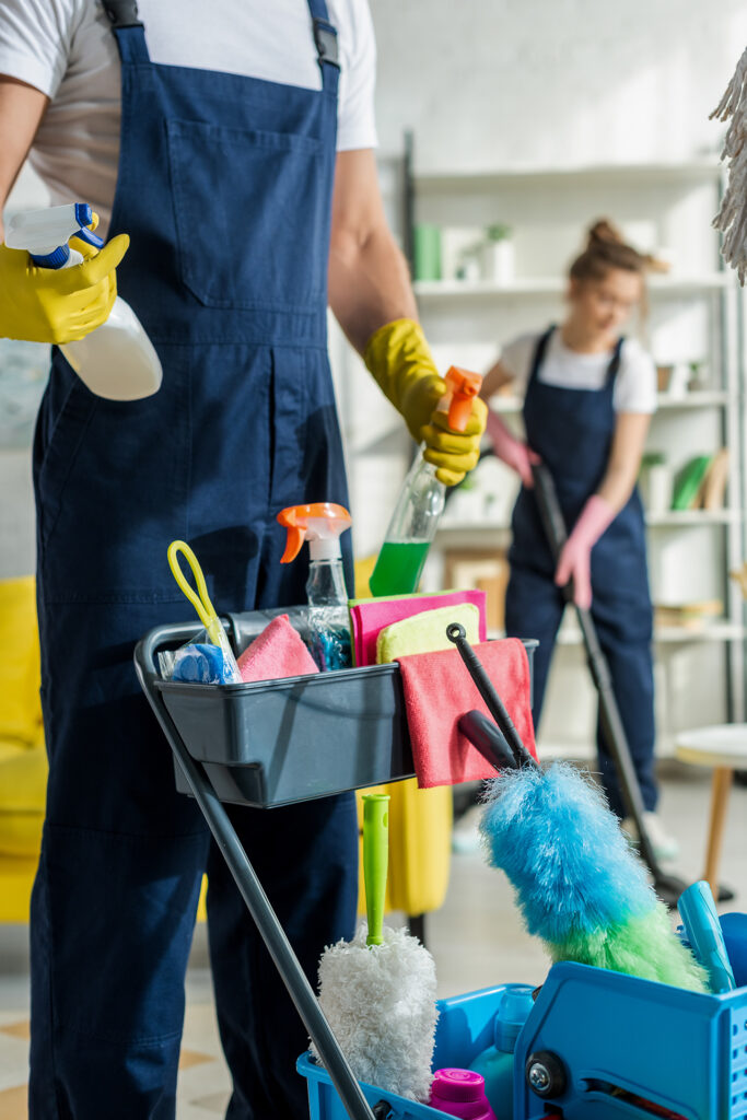 selective focus of cleaner in uniform holding spray bottle near