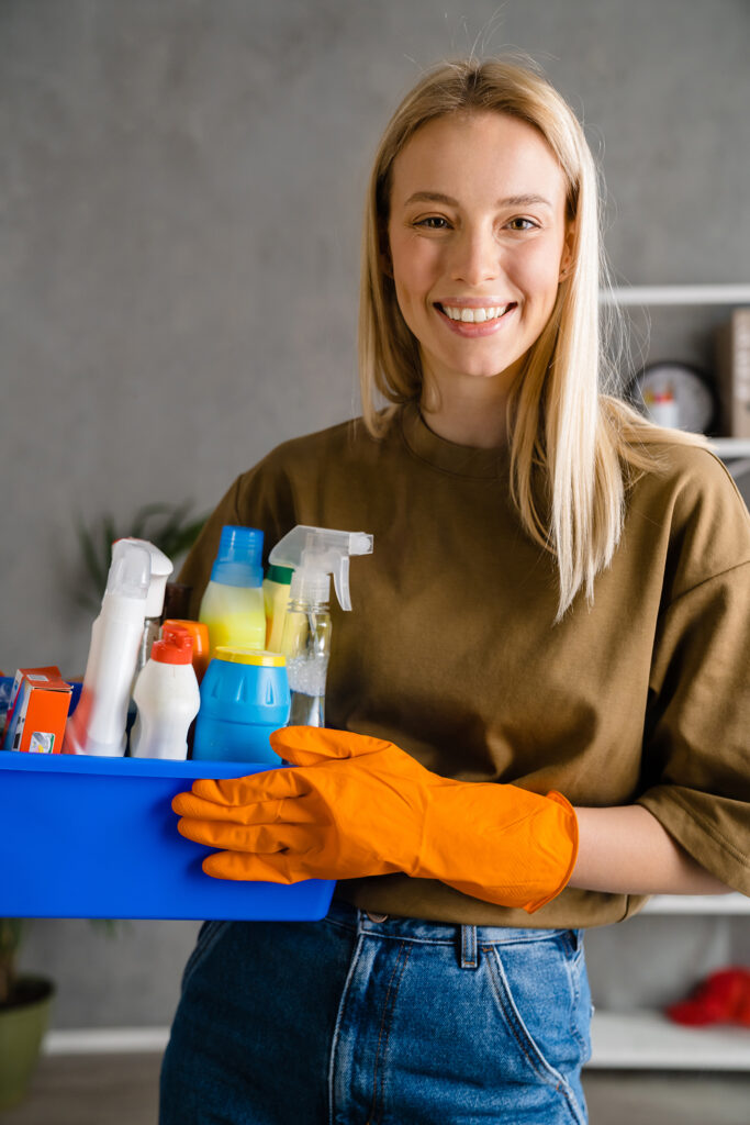 Happy european woman in gloves posing with cleaning product at h